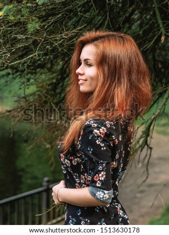 Brunette girl with long hair in dress stands in autumn forest