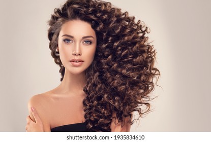 Brunette  girl with long  and   shiny curly  hair .  Beautiful  model woman  with wavy hairstyle  - Shutterstock ID 1935834610