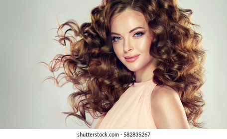 Brunette  Girl With Long  And  Volume Shiny Wavy Hair .  Beautiful  Model With Curly Hairstyle .