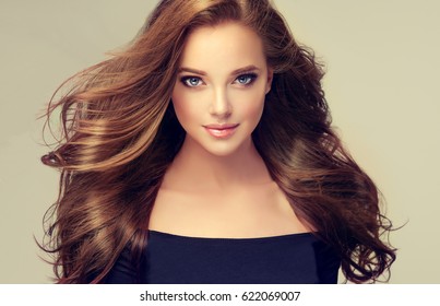 Brunette  Girl With Long  And  Volume Shiny Wavy Hair .  Beautiful  Model With Curly Hairstyle .