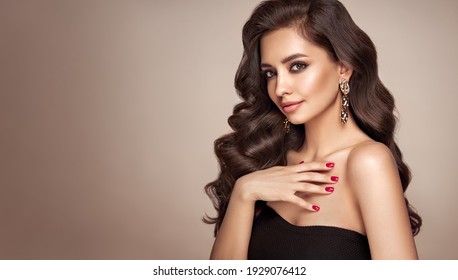 Brunette Girl With Perfect Makeup. Smiling Beautiful Model Woman With Long Curly Hairstyle. Care And Beauty Hair Products. Red Nails Manicure