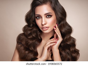 Brunette girl with perfect makeup. Smiling beautiful model woman with long curly hairstyle. Care and beauty hair products. Red nails manicure