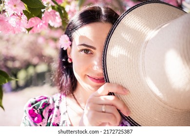 A Brunette Girl In A Straw Hat In A Blooming Garden