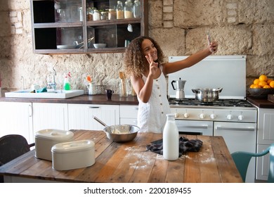 brunette girl taking a selfie while preparing a dessert in the kitchen of her home - Shutterstock ID 2200189455