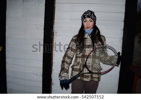 Brunette girl with tennis racket on background of boards