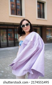 Brunette Girl Walks In The City. Blue Corsage, Lilac Jacket