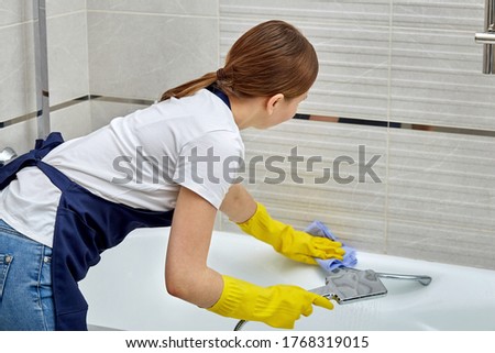 Brunette girl washes the railing in the bathroom, railing for older people.