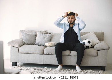 Brunette Guy Sitting On A Coach And Watching Football At Home