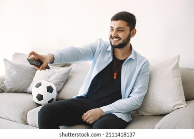 Brunette Guy Sitting On A Coach And Watching Football At Home