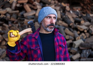 Brunette Handsome Man With Beard Holding Axe And Angry Face.  Wearing Lumberjack Shirt. Wooden Blurry Background. 