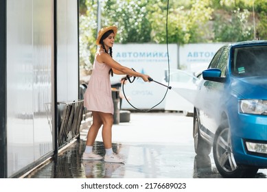 Brunette from a high-pressure hose washes the car - Powered by Shutterstock