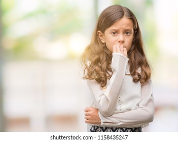 Brunette hispanic girl looking stressed and nervous with hands on mouth biting nails. Anxiety problem.
