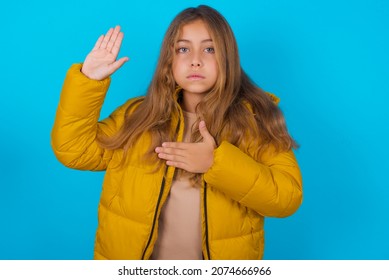 Brunette Kid Girl Wearing Yellow Jacket Over Blue Background  Swearing With Hand On Chest And Open Palm, Making A Loyalty Promise Oath