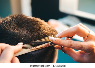 Brunette Man Getting A Haircut By A Professional Hairdresser Using Comb And Grooming Scissors. Closeup View With Shallow Depth Of Field.

