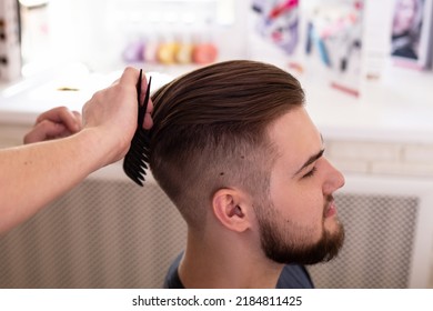 Brunette man with stylish haircut on barbershop background
