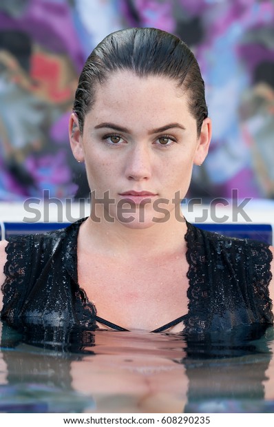 Brunette
model with hair wet and slicked back in a
pool.