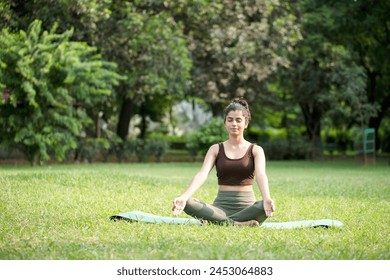 Brunette model in meditation pose sit on yoga mat on green park
 - Powered by Shutterstock