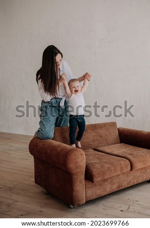 brunette mom plays with her little daughter on a brown sofa
