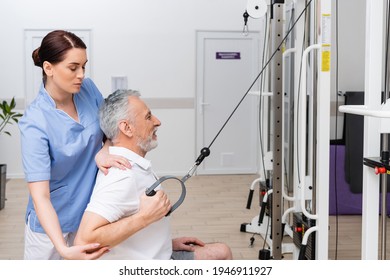 brunette physiotherapist supporting mature man exercising in rehabilitation center - Powered by Shutterstock