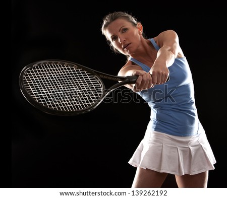 brunette playing tennis on black background