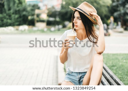 Brunette pretty tourist girl outdoor with cup of cold coffee