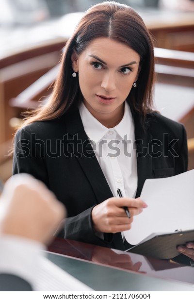 brunette prosecutor looking at blurred judge while
holding lawsuit in
court