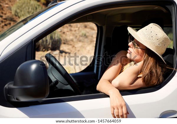Brunette\
resting in car on road trip, looking\
away