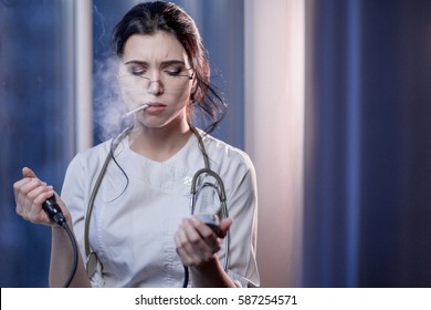 Brunette Sassy Female Nurse In Uniform Smoking A Cigarette Measures The Blood Pressure