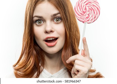 brunette smiling on a light background with a large round striped candy.