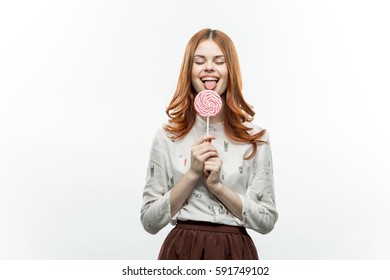 brunette smiling on a light background with a large round striped candy