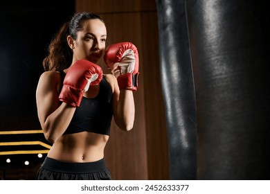 Brunette sportswoman in black top and red boxing gloves training in the gym. - Powered by Shutterstock