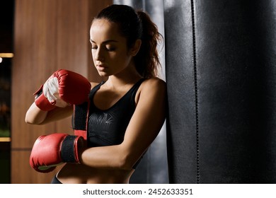 A brunette sportswoman in a black top showcases her strength and skill as she boxing in a gym wearing red boxing gloves. - Powered by Shutterstock