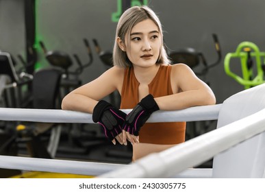 Brunette sportswoman standing at boxing ring during taking break time exercising in boxing gym - Powered by Shutterstock