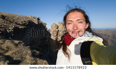Brunette takes a selfie on a smartphone against the background of beautiful mountains
