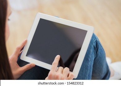 Brunette teen using a tablet pc sitting on the floor in a living room - Powered by Shutterstock