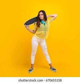 Brunette Teenage Girl In Sheer Shirt Holding Skateboard Looking At Camera.