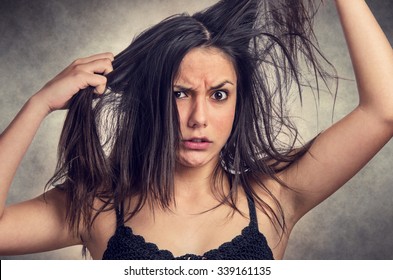 Brunette teenager girl with anger expression pulling her messy hair