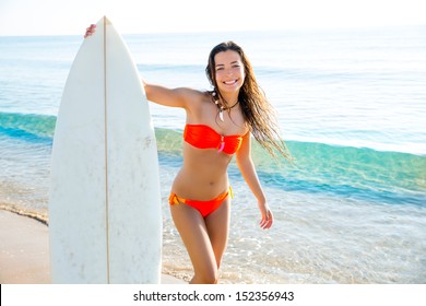 Brunette teenager surfer bikini girl with surfboard on beach shore