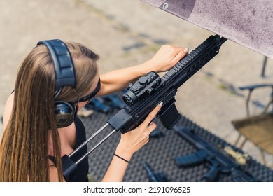 Brunette White Woman In Safety Headphones Pracrticing Using Submachine Gun On Outdoor Firing Range, Horizontal Shot. . High Quality Photo