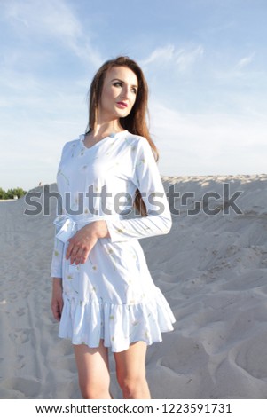 brunette woman in beach sand in blue dress