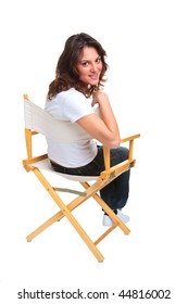 A Brunette Woman In Casual Clothing Sat On A Directors Chair Looking Back Over Her Shoulder, Isolated On A White Background.