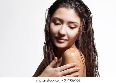 Brunette woman cleans the skin of the body coffee scrub on a white background isolated