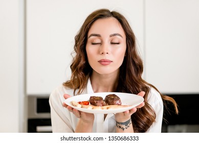 Brunette woman cooking and eating red meat steak with glass of red wine. Housewife concept
