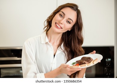 Brunette Woman Cooking And Eating Red Meat Steak With Glass Of Red Wine. Housewife Concept