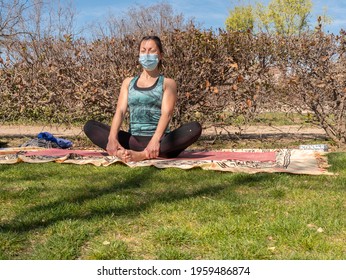 A Brunette Woman Doing Yoga Class In A Park On A Sunny Day And Wearing A Face Mask