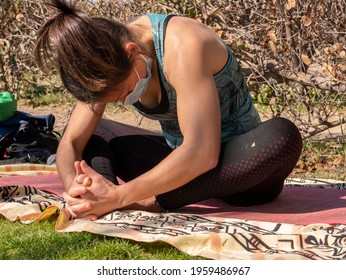 A Brunette Woman Doing Yoga Class In A Park On A Sunny Day And Wearing A Face Mask