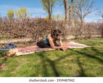 A Brunette Woman Doing Yoga Class In A Park On A Sunny Day And Wearing A Face Mask