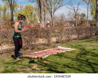 A Brunette Woman Doing Yoga Class In A Park On A Sunny Day And Wearing A Face Mask