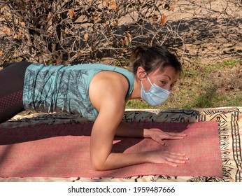 A Brunette Woman Doing Yoga Class In A Park On A Sunny Day And Wearing A Face Mask