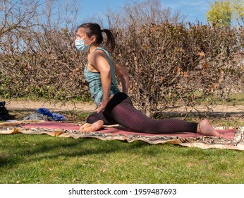 A Brunette Woman Doing Yoga Class In A Park On A Sunny Day And Wearing A Face Mask